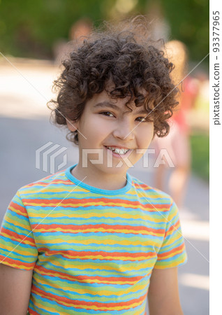 Friendly smiling boy with dark curly hair 93377965