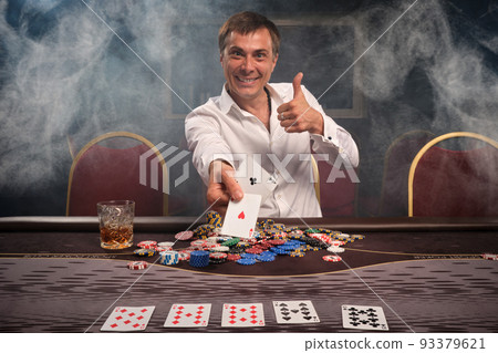 Handsome emotional man is playing poker sitting at the table in casino. Handsome emotional man is playing poker sitting at the table in casino. 93379621