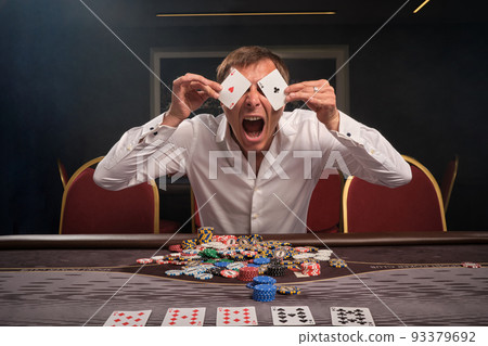 Handsome emotional man is playing poker sitting at the table in casino. Handsome emotional man is playing poker sitting at the table in casino. 93379692