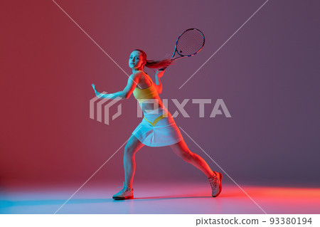 Full length portrait of young woman playing tennis isolated on dark background in neon. Healthy lifestyle, fitness, sport, exercise concept. Full length portrait of young woman playing tennis isolated on dark background in neon. Healthy lifestyle, fitness, sport, exercise concept. 93380194