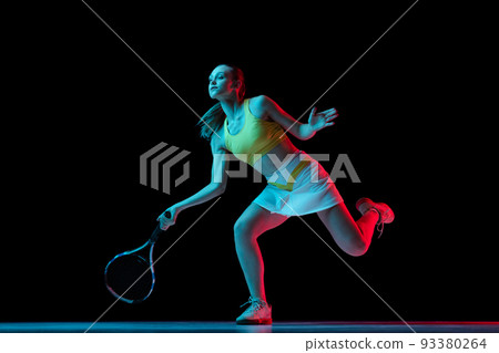 Young woman, professional tennis player training isolated on blue background in neon. 93380264
