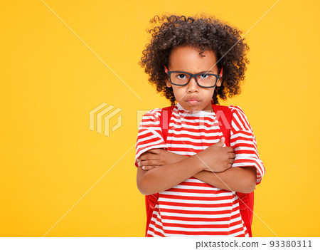 Funny ethnic schoolboy with making face against yellow background 93380311