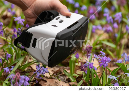 Virtual reality headset glasses in hand in flowers 93380917
