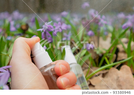 Hand spray clear drops from bottle in flowers 93380946