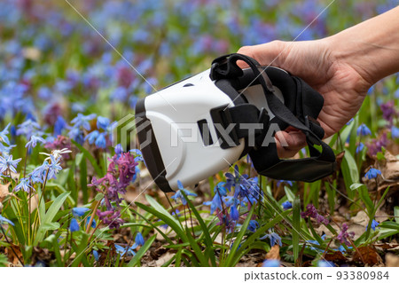 Virtual reality headset glasses in hand in flowers Virtual reality headset glasses in hand in flowers 93380984