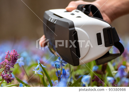 Virtual reality headset glasses in hand in flowers Virtual reality headset glasses in hand in flowers 93380986