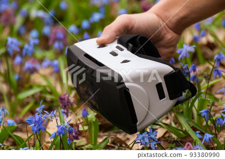 Virtual reality headset glasses in hand in flowers 93380990