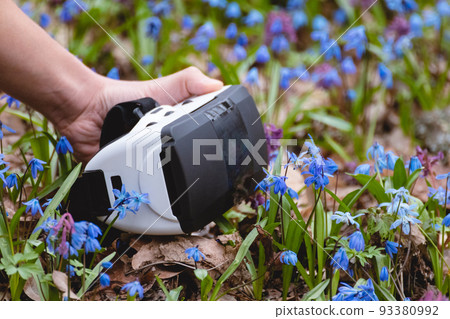 Virtual reality headset glasses in hand in flowers 93380992