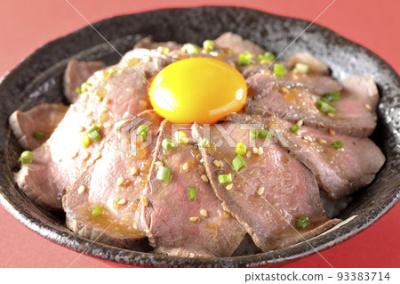 Roast beef rice bowl topped with raw egg yolk, green onion, and white sesame seeds Roast beef rice bowl topped with raw egg yolk, green onion, and white sesame seeds 93383714