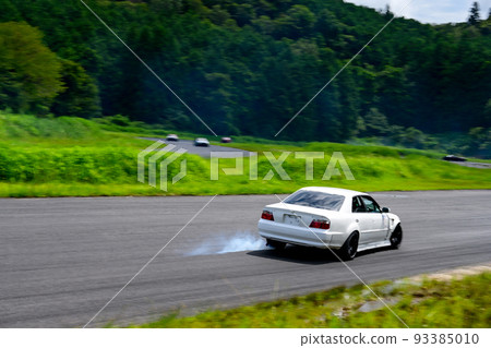 A hand-made race car running on a circuit course surrounded by greenery 93385010
