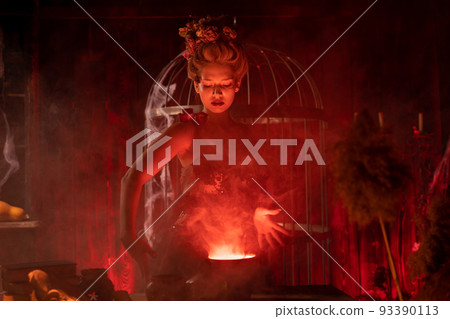 Halloween Witch with cauldron. Beautiful young woman conjuring, making witchcraft 93390113