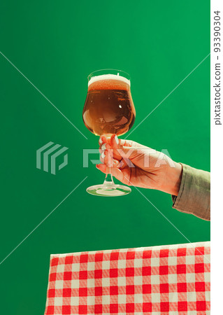 Female hand holding glass of cold dark beer over dark green background. Oktoberfest, vacation, happiness, festival and ad concept. Female hand holding glass of cold dark beer over dark green background. Oktoberfest, vacation, happiness, festival and ad concept. 93390304
