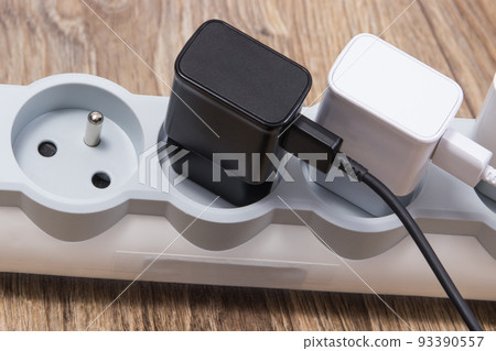 Mobile phone chargers connected to electrical power strip. Various devices charging 93390557