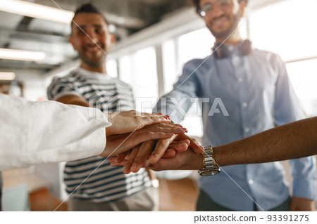 Close up of Happy group multi ethnic coworkers stacked hands together as concept of corporate unity Close up of Happy group multi ethnic coworkers stacked hands together as concept of corporate unity 93391275