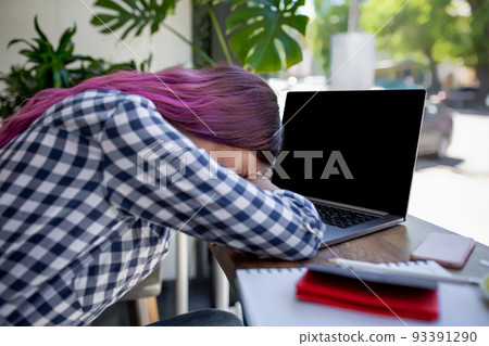 Young woman lying on her arms on the table in cafe in front of laptop with cup of coffee, sleepy. Young woman lying on her arms on the table in cafe in front of laptop with cup of coffee, sleepy. 93391290