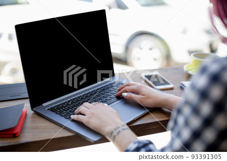 Woman typing on notebook with blank screen with copy space for your text or advertising content, sitting at wooden table Woman typing on notebook with blank screen with copy space for your text or advertising content, sitting at wooden table 93391305