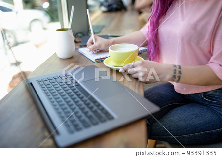 Woman typing on notebook with blank screen, sitting at wooden table Woman typing on notebook with blank screen, sitting at wooden table 93391335