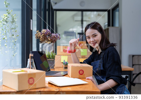 Freelance woman working at home with Online Parcel delivery. SME and packaging delivery concept Freelance woman working at home with Online Parcel delivery. SME and packaging delivery concept 93391336