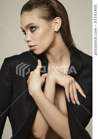 Fashion portrait of a beautiful young woman posing in a black evening suit 93391408