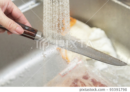 A woman's hand washing a knife 93391798