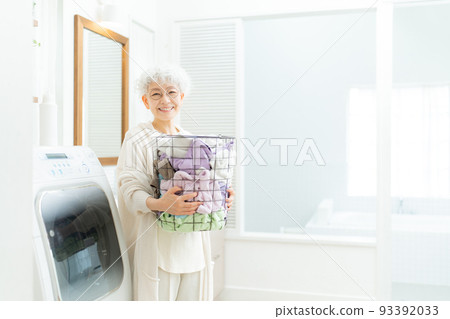 Senior woman doing laundry in laundry room 93392033