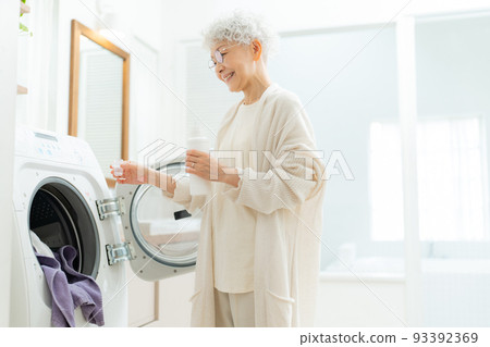 將洗衣粉放入洗衣機的高級婦女 93392369