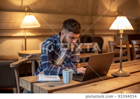 Young professional surfing the Internet on his laptop in a cafe 93394054