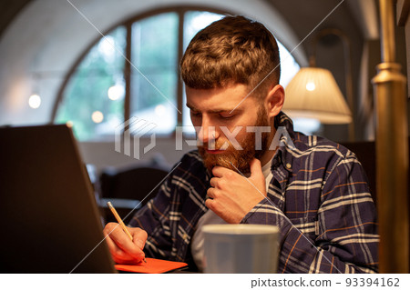 Casual business man or freelancer planning his work on notebook, working on laptop computer with smart phone, cup of coffee on table at coffee shop or home office. 93394162