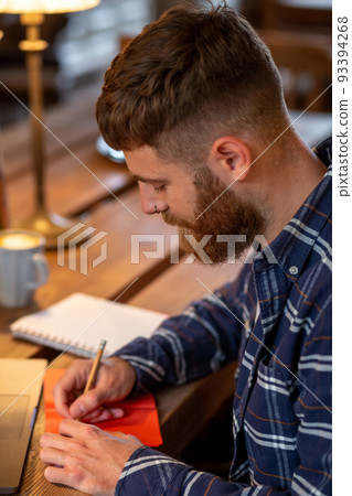 Casual business man or freelancer planning his work on notebook, working on laptop computer with smart phone, cup of coffee on table at coffee shop or home office. Casual business man or freelancer planning his work on notebook, working on laptop computer with smart phone, cup of coffee on table at coffee shop or home office. 93394268