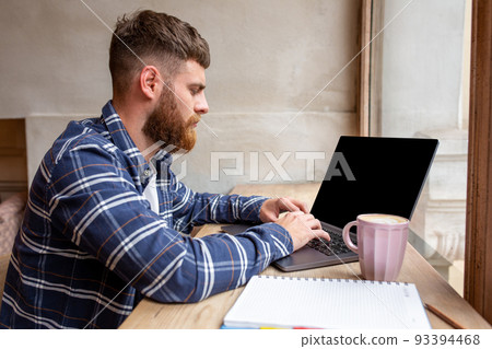 Young man chatting via net-book during work break in coffee shop, male sitting in front open laptop computer with blank copy space screen. Young man chatting via net-book during work break in coffee shop, male sitting in front open laptop computer with blank copy space screen. 93394468