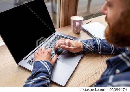 Cropped image of young man chatting via net-book during work break in coffee shop, male sitting in front open laptop computer with blank copy space screen. 93394474