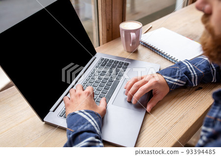 Cropped image of young man chatting via net-book during work break in coffee shop, male sitting in front open laptop computer with blank copy space screen. 93394485