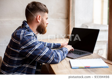 Young man chatting via net-book during work break in coffee shop, male sitting in front open laptop computer with blank copy space screen. 93394498