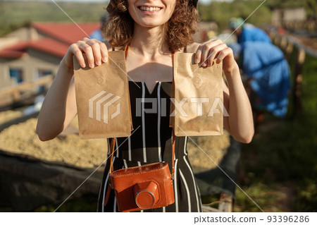 Smiling woman holding two paper bags with coffee beans 93396286