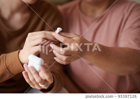 Closeup image of grandson giving grandmother new earbuds he bought for her Closeup image of grandson giving grandmother new earbuds he bought for her 93397126