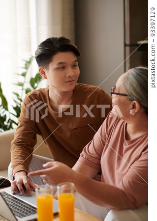 Senior woman asking grandson to show how she can pay bills online Senior woman asking grandson to show how she can pay bills online 93397129