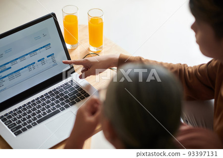 Teenage boy showing grandmother how to pay utility bills online 93397131