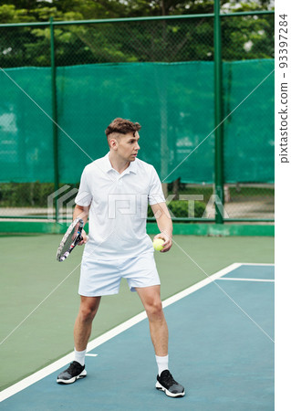 Serious tennis player serving ball on outdoor court 93397284