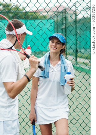 Smiling female tennis player talking to friend after game on outdoor court 93397286