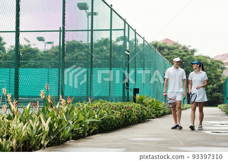 Smiling young couple taking when walking to tennis court Smiling young couple taking when walking to tennis court 93397310