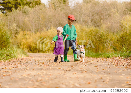 Little children walking with family dog along country dirt road 93398602