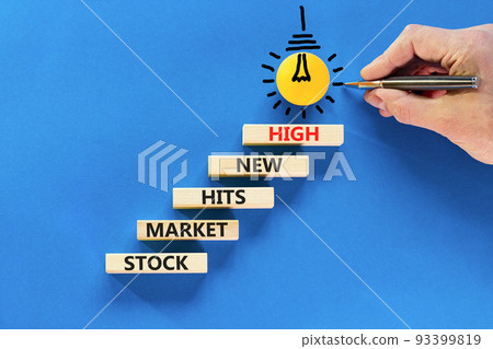 Stock market hits new high symbol. Concept words Stock market hits new high on wooden blocks on a beautiful blue background. Businessman hand. Business stock market hits new high concept. Copy space. 93399819