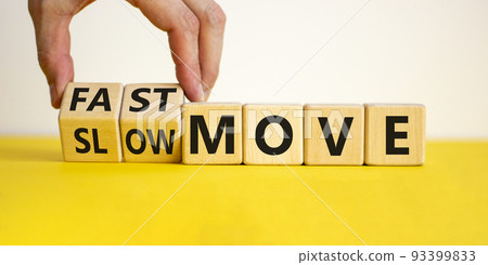 Time to fast move symbol. Businessman turns a wooden cube and changes words 'slow move' to 'fast move'. Beautiful yellow table, white background, copy space. Business and slow or fast move concept. 93399833