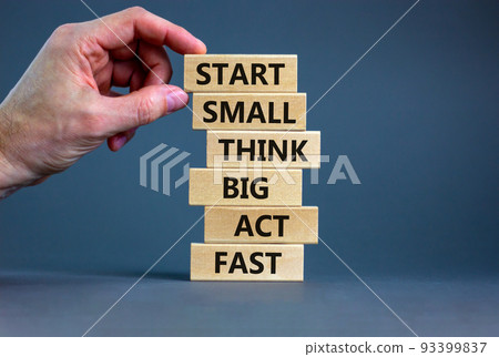 Start small think big symbol. Words 'Start small think big act fast' on wooden blocks on a beautiful grey background. Businessman hand. Business, motivational and start small think big concept. 93399837