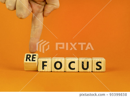 Focus or refocus symbol. Businessman turns wooden cubes and changes the concept word focus to refocus. Beautiful orange table orange background. Business focus or refocus concept. Copy space. 93399838