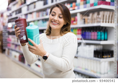 Young Latina choosing haircare cosmetics in specialized boutique Young Latina choosing haircare cosmetics in specialized boutique 93400541