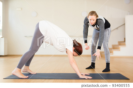 Pregnant woman practices yoga with an instructor. Downward Dog Pose or Adho Mukha Svanasana Pregnant woman practices yoga with an instructor. Downward Dog Pose or Adho Mukha Svanasana 93400555