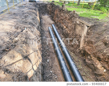 laying of underground communications for residential buildings. black plumbing pipes made of durable and reliable material are buried deep in an earthen ditch 93400817