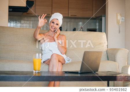 Beautiful woman sitting on the sofa at home using smartphone doing happy thumbs up gesture with hand. approving expression looking at the camera showing success 93401982