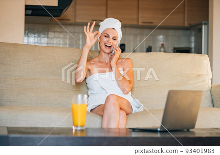 Beautiful woman sitting on the sofa at home using smartphone doing happy thumbs up gesture with hand. approving expression looking at the camera showing success 93401983